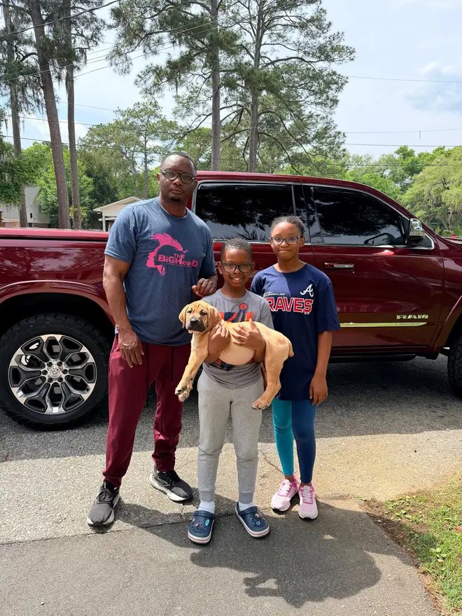 A family collecting their South African Boerboel puppy from LowCountry Boerboels, the youngest child carrying him on the driveway